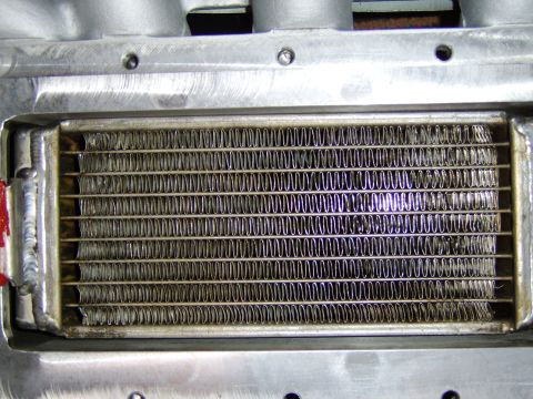 1996 Mercury Grand Marquis - Close-up of a heat exchanger or intercooler core showing rows of finned aluminum tubes with serpentine cooling fins, mounted in a welded al…
