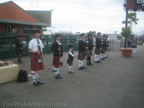 1968 Ford Mustang - Photograph of a row of bagpipers in tartan kilts standing at an outdoor venue.