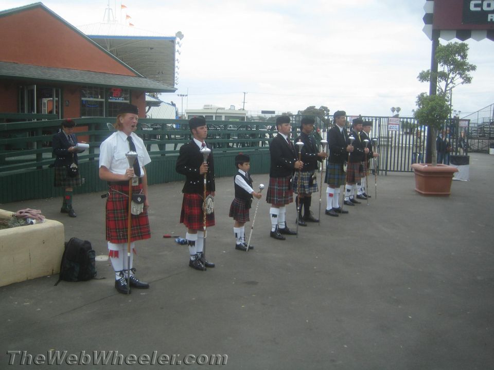 Line of bagpipers in kilts standing outdoors