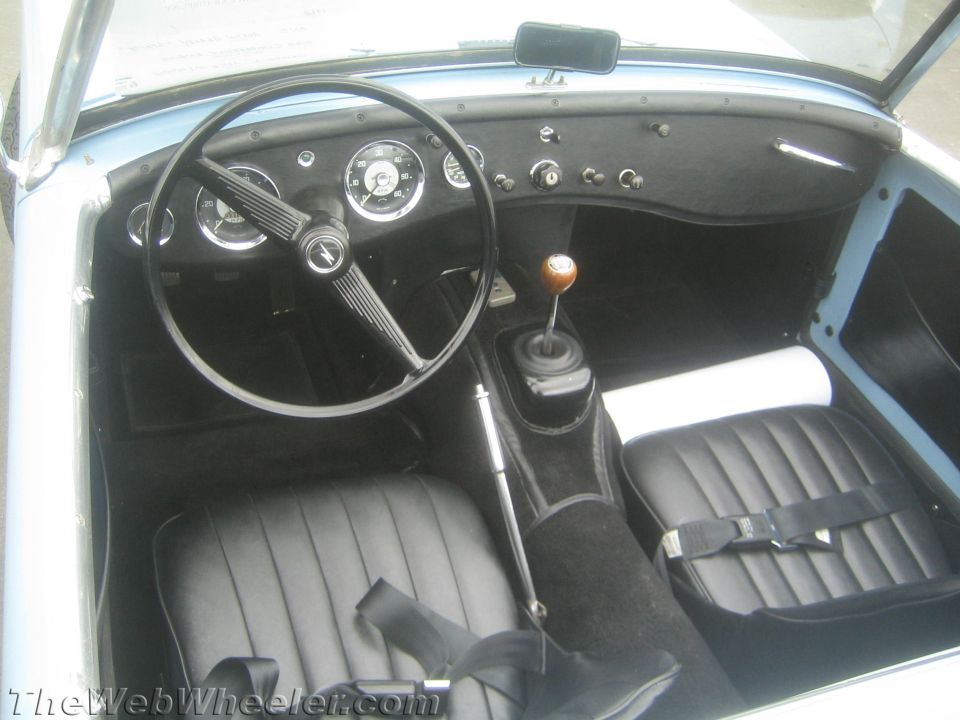 Interior of an Austin-Healey Sprite showing steering wheel, gauges and black seats