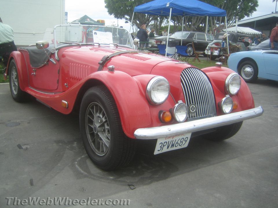 Front three-quarter view of a red Morgan roadster at a car show