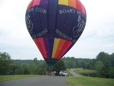 1971 Ford Ranchero - A multicolored hot air balloon lettered "BOAR'S HEAD INN" and "BIRDWOOD GOLF COURSE" lands on a paved country lane while a small crew stand…