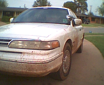 1995 Ford Crown Victoria - A muddy 1995 Ford Crown Victoria is parked on a driveway, viewed from the front three-quarter angle.