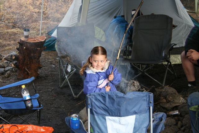 Young girl roasting a marshmallow on a stick at a campsite