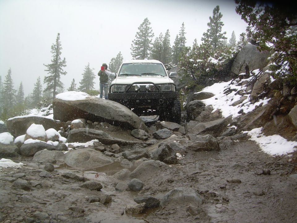 White Toyota 4Runner on a snowy, rocky, and muddy off-road trail.
