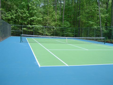 1979 Ford Ranchero - A tennis court is shown with a green playing surface and blue out of bounds area, surrounded by a fence and trees.
