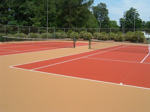 1979 Ford Ranchero - An outdoor tennis court with two nets dividing the courts. The courts are painted in two colors, red and tan, with white lines marking the…