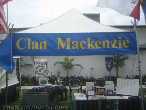 1968 Ford Mustang - Outdoor festival photo showing a blue Clan Mackenzie banner over a vendor display booth, not a technical document.