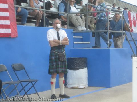 1968 Ford Mustang - Event photo of a man wearing a kilt beside blue grandstands, not a technical document.