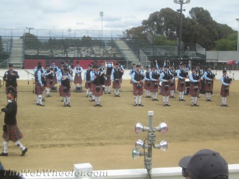 1968 Ford Mustang - Event photo of a uniformed bagpipe band performing on a dirt field, not a technical document.