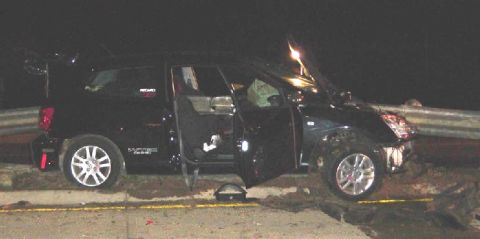 Black SUV with driver's side doors open, damaged front end, parked on roadside