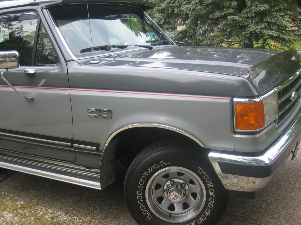 1990 Ford Bronco passenger side front 3/4 view, grey with chrome trim