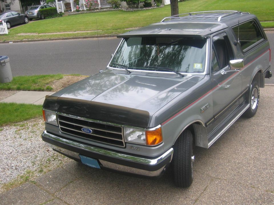 1990 Ford Bronco parked on a driveway, front 3/4 view.