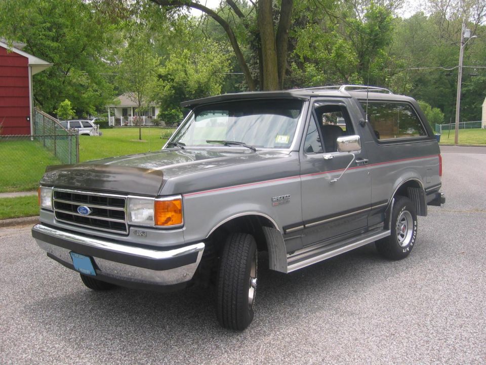 1990 Ford Bronco in gray two-tone parked on a residential street, 3/4 front view