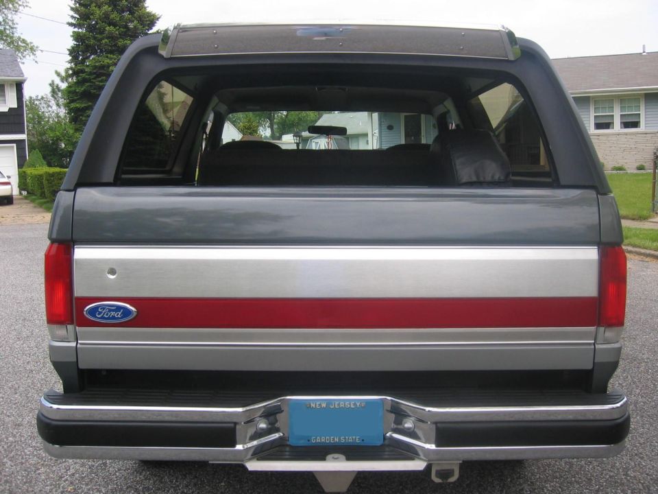 Rear view of a gray 1990 Ford Bronco with a red stripe and New Jersey license plate.