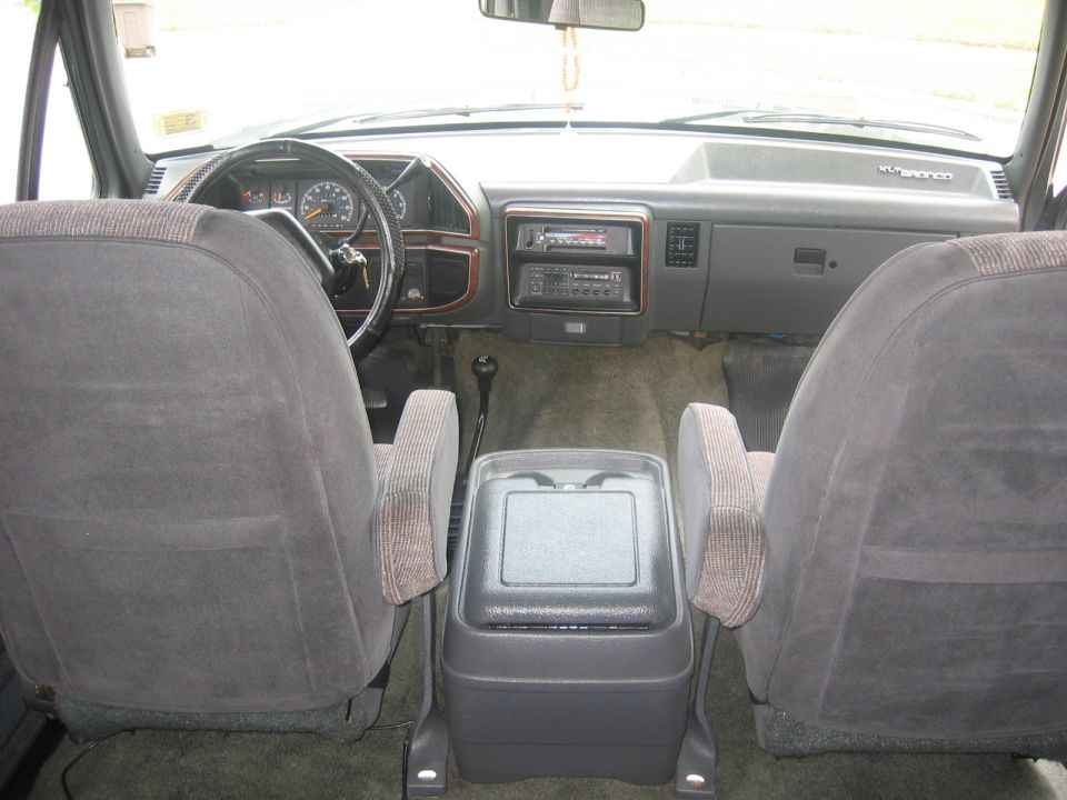 Interior view of a 1990 Ford Bronco, showing dashboard, seats, and center console.