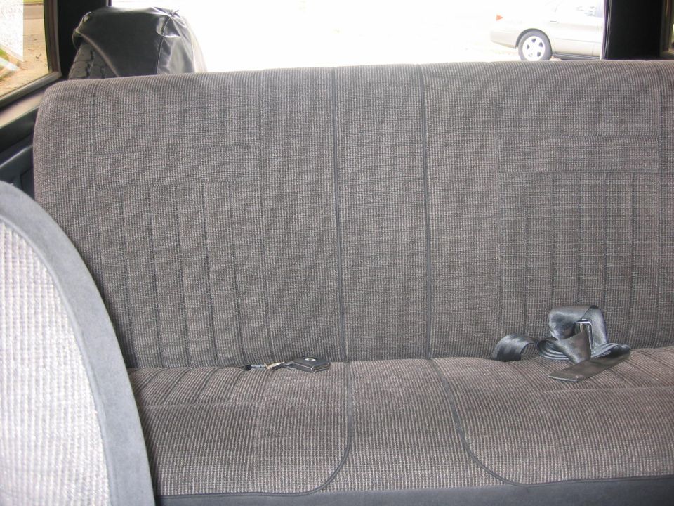 Gray fabric bench seat in a vehicle with keys and a seatbelt.