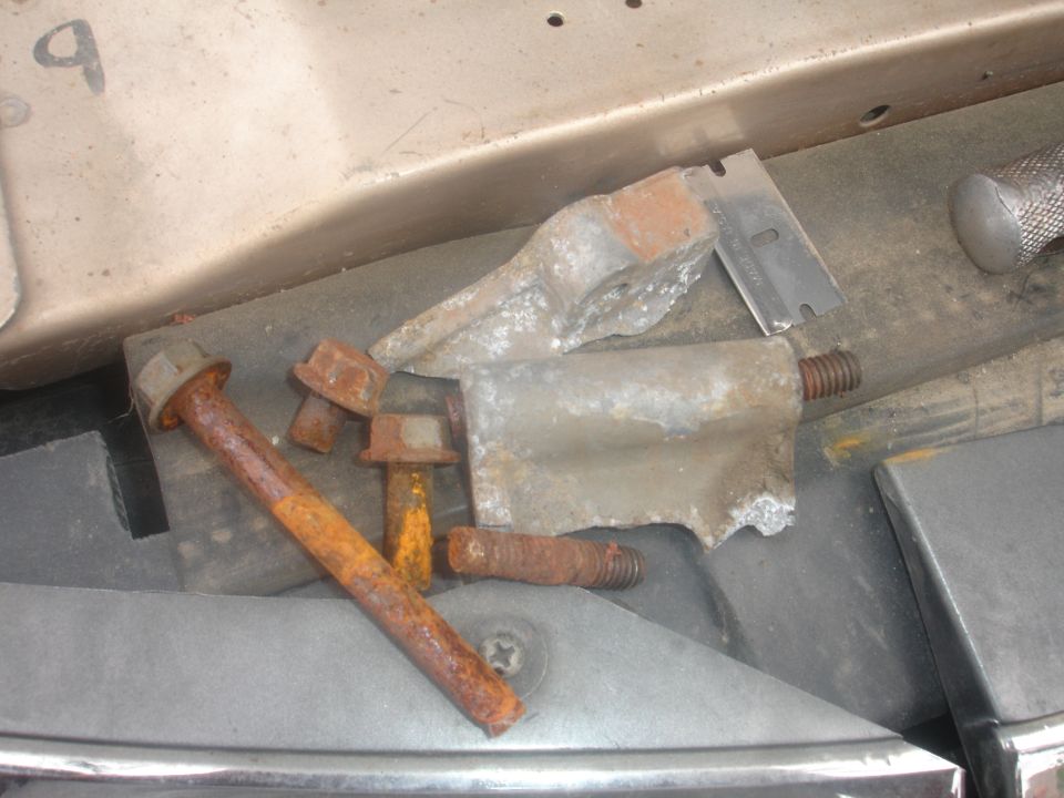 Rusty bolts and a razor blade on a dark surface.