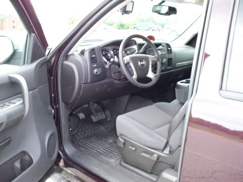 1996 Ford Bronco - The interior of a dark red pickup truck is shown, focusing on the driver's side door, dashboard, and front seat. The steering wheel, center…