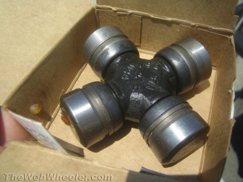 1968 Ford Mustang - Close-up product photo of a u-joint cross and caps in a cardboard box, not a technical document.