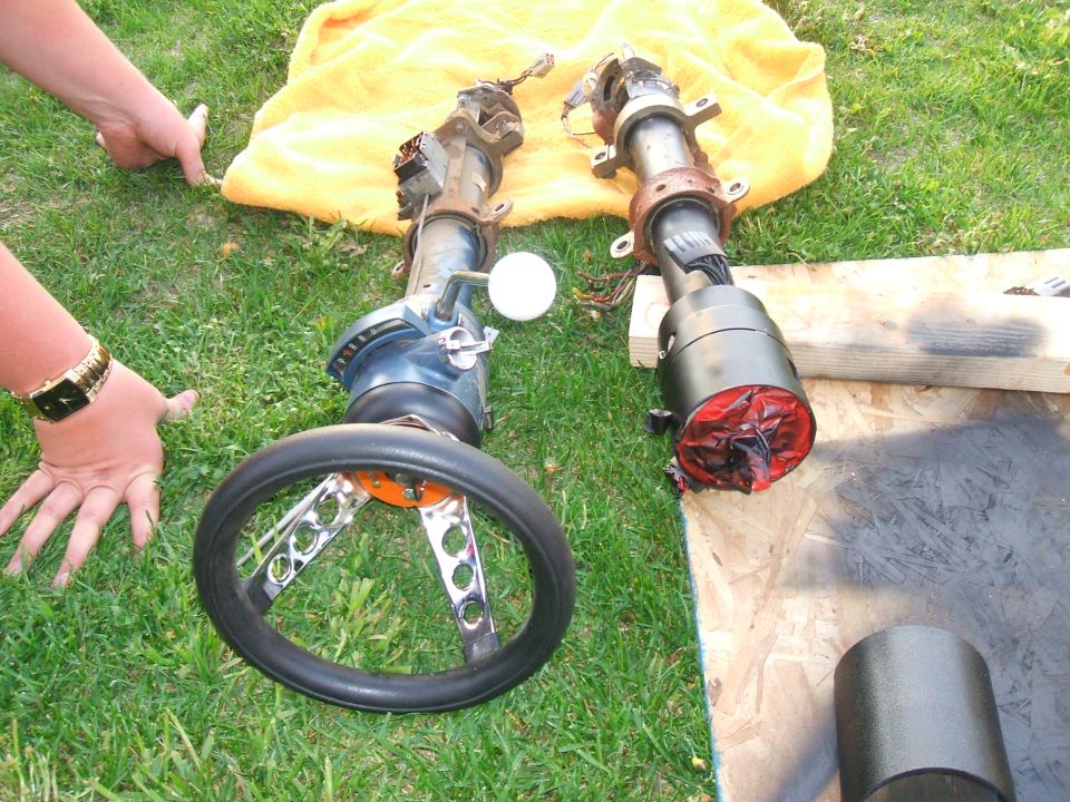 Two car steering columns and steering wheels on grass