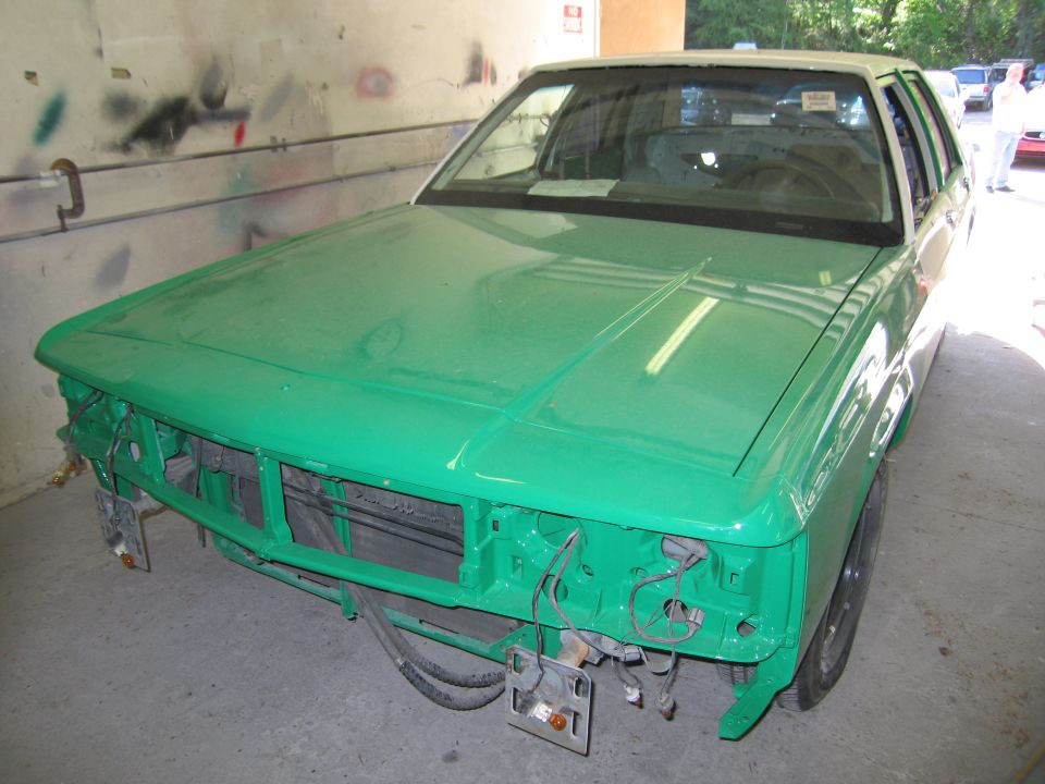 Front of a green sedan with bumper removed during bodywork