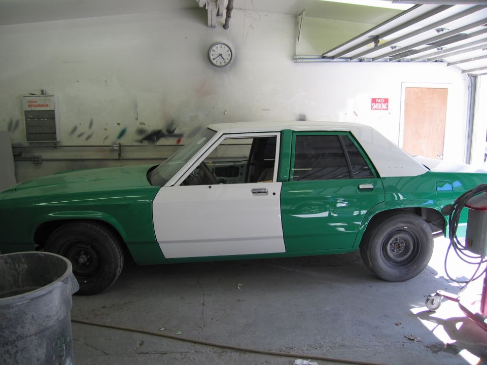 Side profile of a green and white sedan in a garage