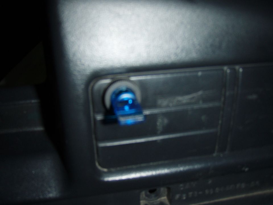 Small blue switch mounted in a blank panel on a grey plastic dash trim piece
