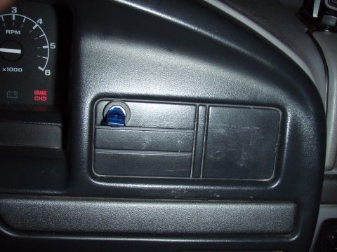 1995 Ford F-150 - Daylight close-up of a gray truck dash panel showing a blue-lensed rocker switch installed in one of the blank switch positions beside the…