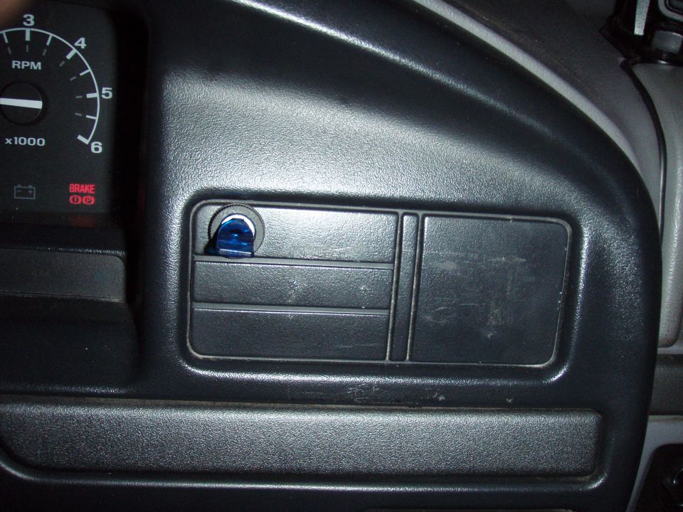 Blue rocker switch installed in a blank dash position next to the tachometer