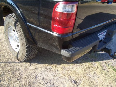 2003 Ford Ranger - A black 2003 Ford Ranger shows damage to its rear quarter panel and bumper, with a visible tire and taillight.