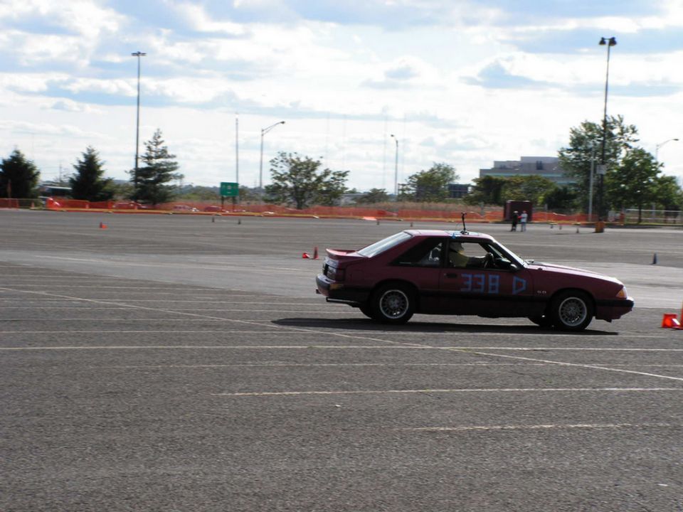 Red 1990 Ford Mustang with racing numbers 338 D on door, seen from 3/4 front