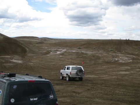 1994 Ford Bronco - A white Ford Bronco navigates a sandy terrain with another vehicle in the foreground.