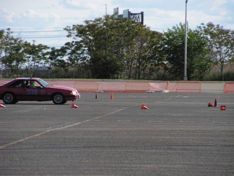 1990 Ford Mustang - A red 1990 Ford Mustang navigates an autocross course marked by orange cones.