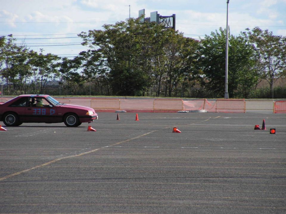 Red 1990 Ford Mustang in side view on a race course with orange cones