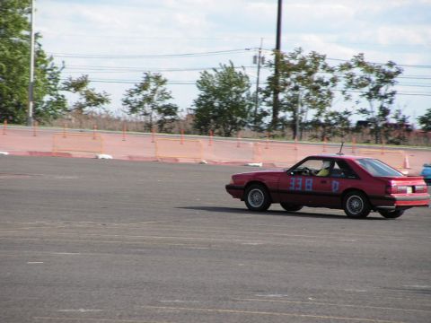 1990 Ford Mustang - A red coupe with racing numbers participates in an autocross event.