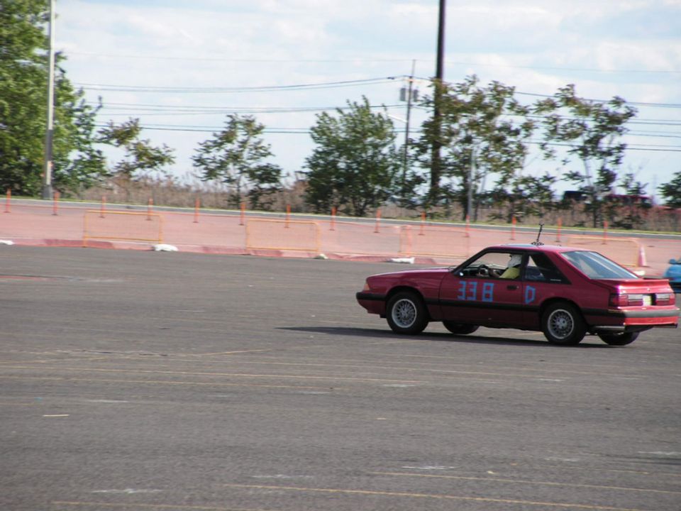 Red coupe with racing numbers 338 D on the side, seen from the side at an autocross event
