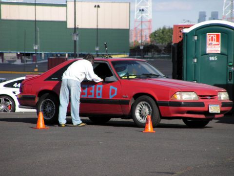 1990 Ford Mustang - A red 1990 Ford Mustang is parked on asphalt, with a person leaning into the driver's side window.