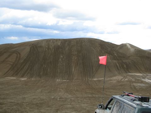 1994 Ford Bronco - A vast expanse of sand dunes marked with tire tracks under a cloudy sky.