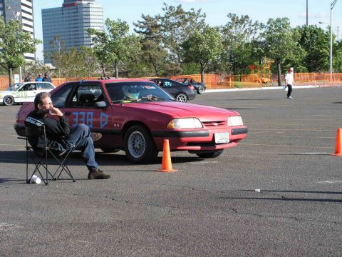 1990 Ford Mustang - A red 1990 Ford Mustang coupe is parked on asphalt, with racing numbers visible on its side.