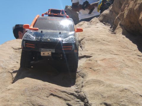 1988 Ford Bronco - An RC car navigates a rocky trail, with another vehicle and people visible in the background.