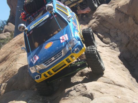 1988 Ford Bronco - RC rock crawler navigates a steep, rocky terrain with another vehicle in the background.