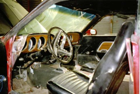 1969 Ford Mustang - The interior of a classic car shows its dashboard, steering wheel, and seats, with visible wood grain accents.