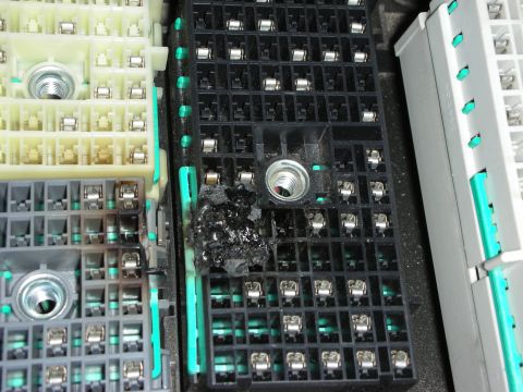 1998 Ford Crown Victoria - Close-up of multi-pin connector blocks in a fuse box showing burnt, melted black residue around a terminal.