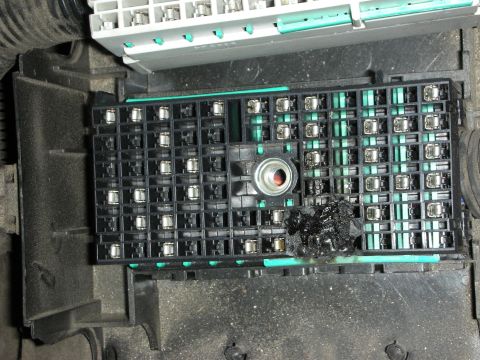 1998 Ford Crown Victoria - Black fuse and relay socket panel removed from a vehicle, showing burnt melted plastic near a center terminal.
