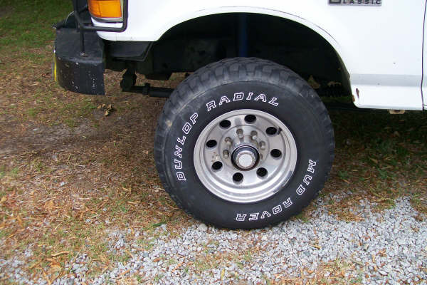 Front wheel and fender of a white truck with Dunlop Mud Rover tires