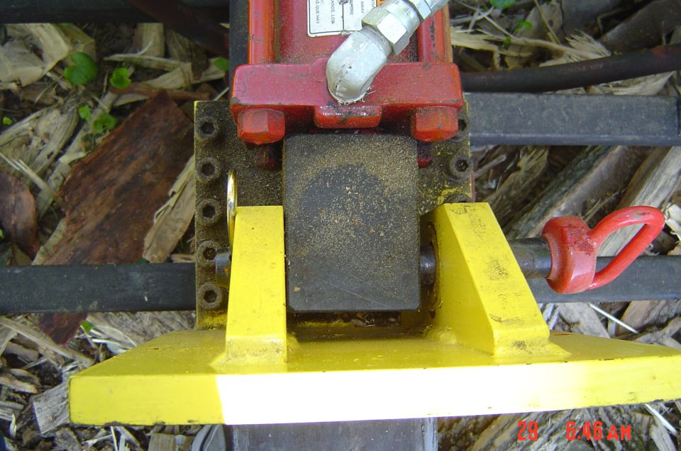 Red and yellow hydraulic jack component with metal rod and red loop handle