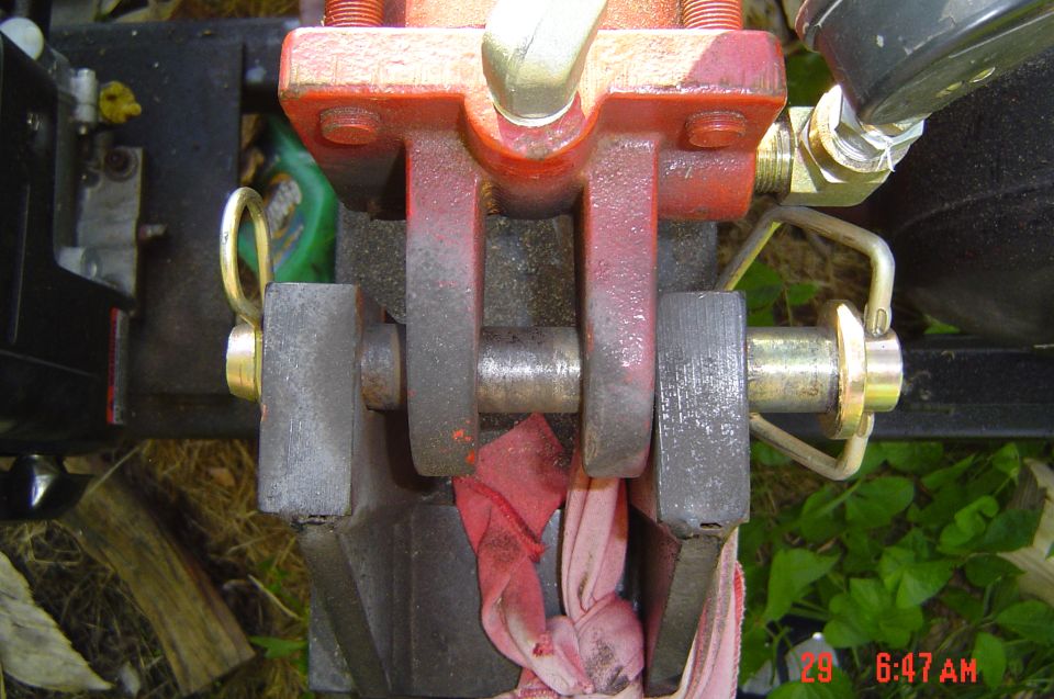 Close-up of hydraulic cylinder linkage with red and gray metal parts