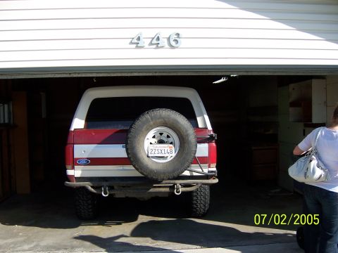 1991 Ford Bronco - Rear view of a 1991 Ford Bronco parked in a garage, showing the spare tire and license plate.