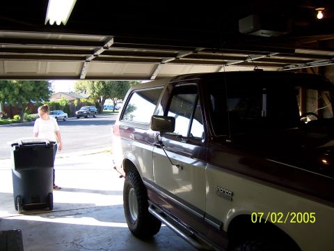 1991 Ford Bronco - A 1991 Ford Bronco is parked inside a garage with the door open, showing a street scene outside.
